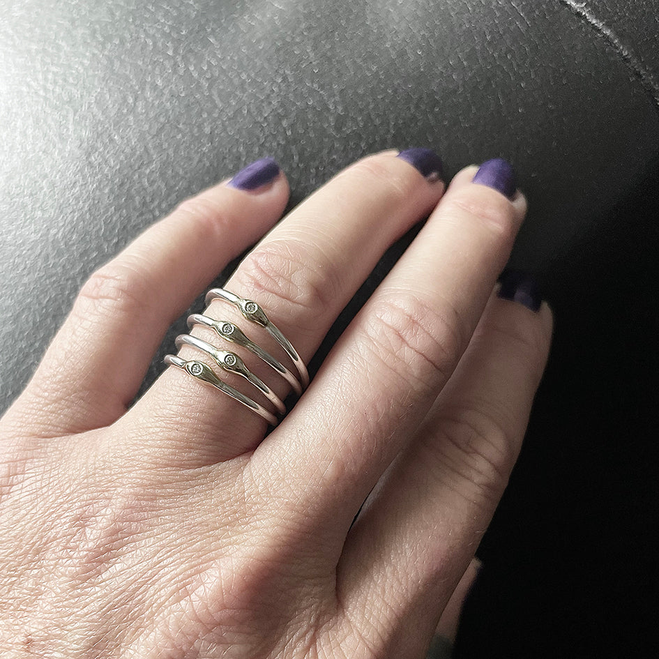 Hand wearing multiple silver rings with gold pearl and diamonds