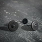 Black round ear studs with black raw diamond on a textured gray surface