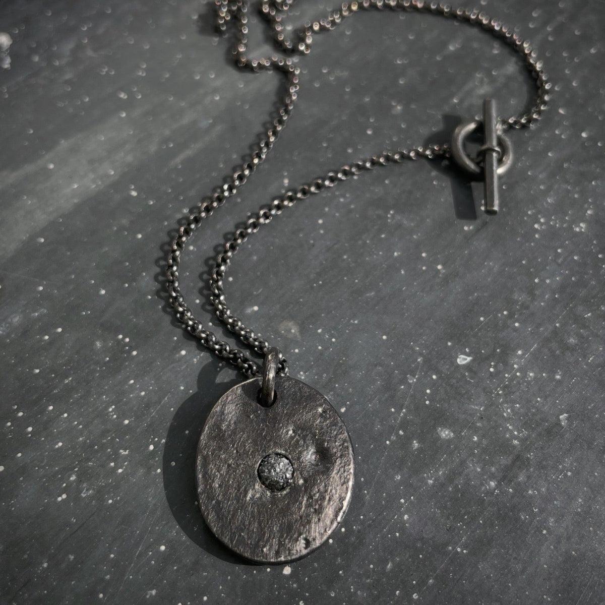 Oxidised silver necklace with a round pendant with raw black diamond