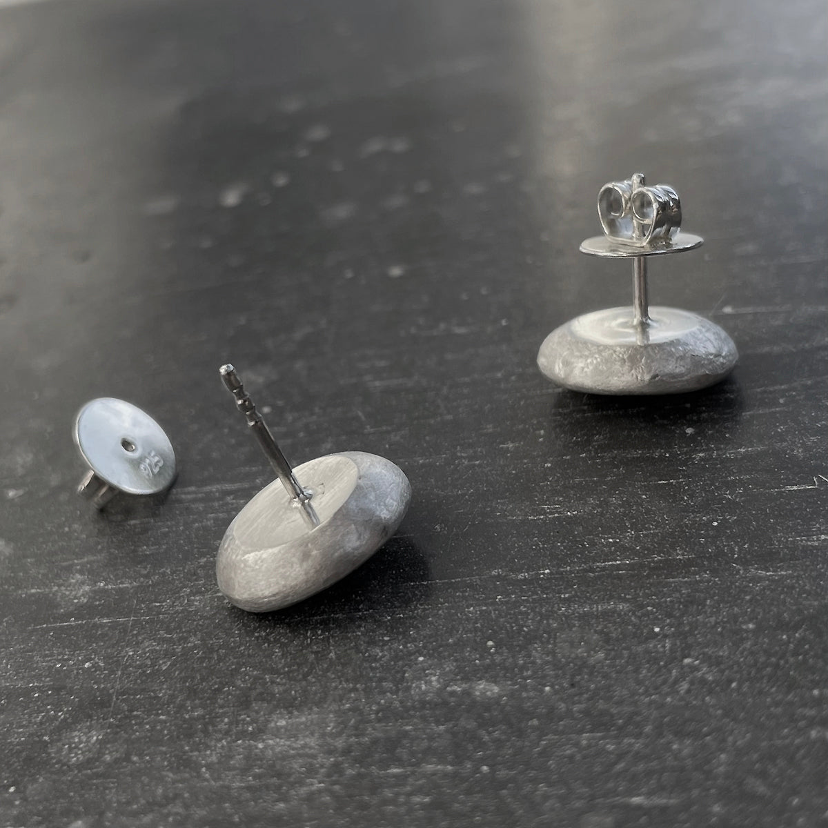 Silver earrings on a dark surface