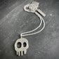 Silver skull pendant necklace on a dark textured surface